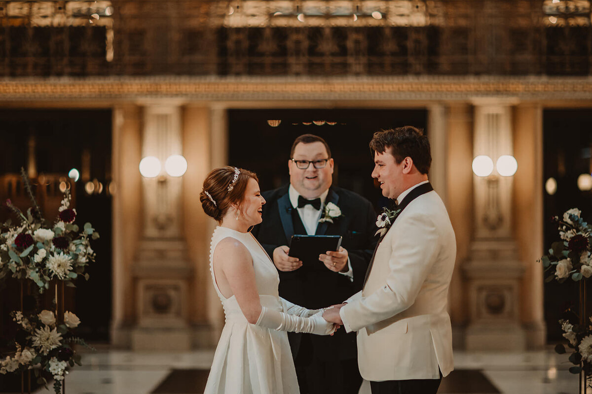 Newlyweds holding hands as they say their vows 