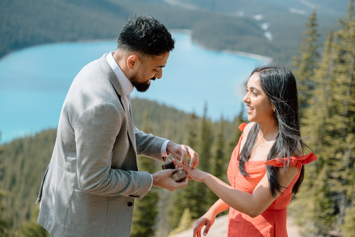 Close-up moment of engagement ring at Moraine Lake proposal with turquoise water backdrop.