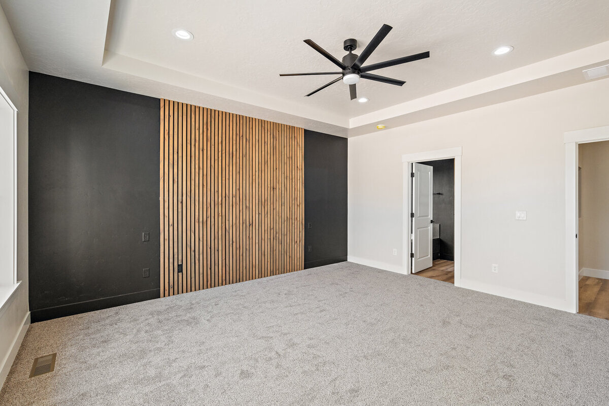 empty living room space with light carpet painted black and wooden accent wall