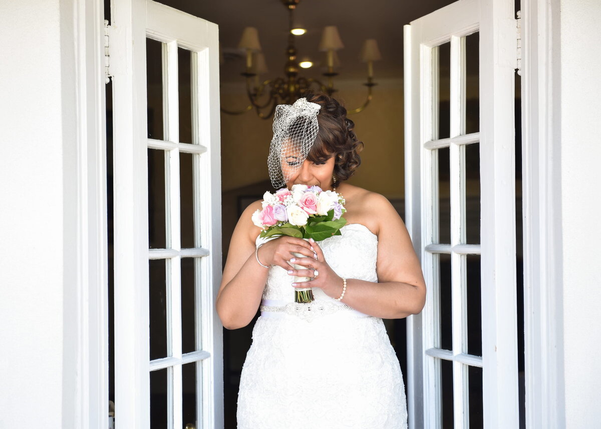 Bride with bouquet standing at a doorway, wedding day photo.