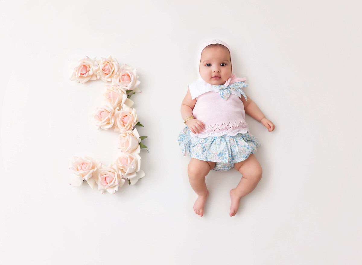 Baby girl lying on her back during a 3-month baby photoshoot captured in NYC by Rochel Konik Photography