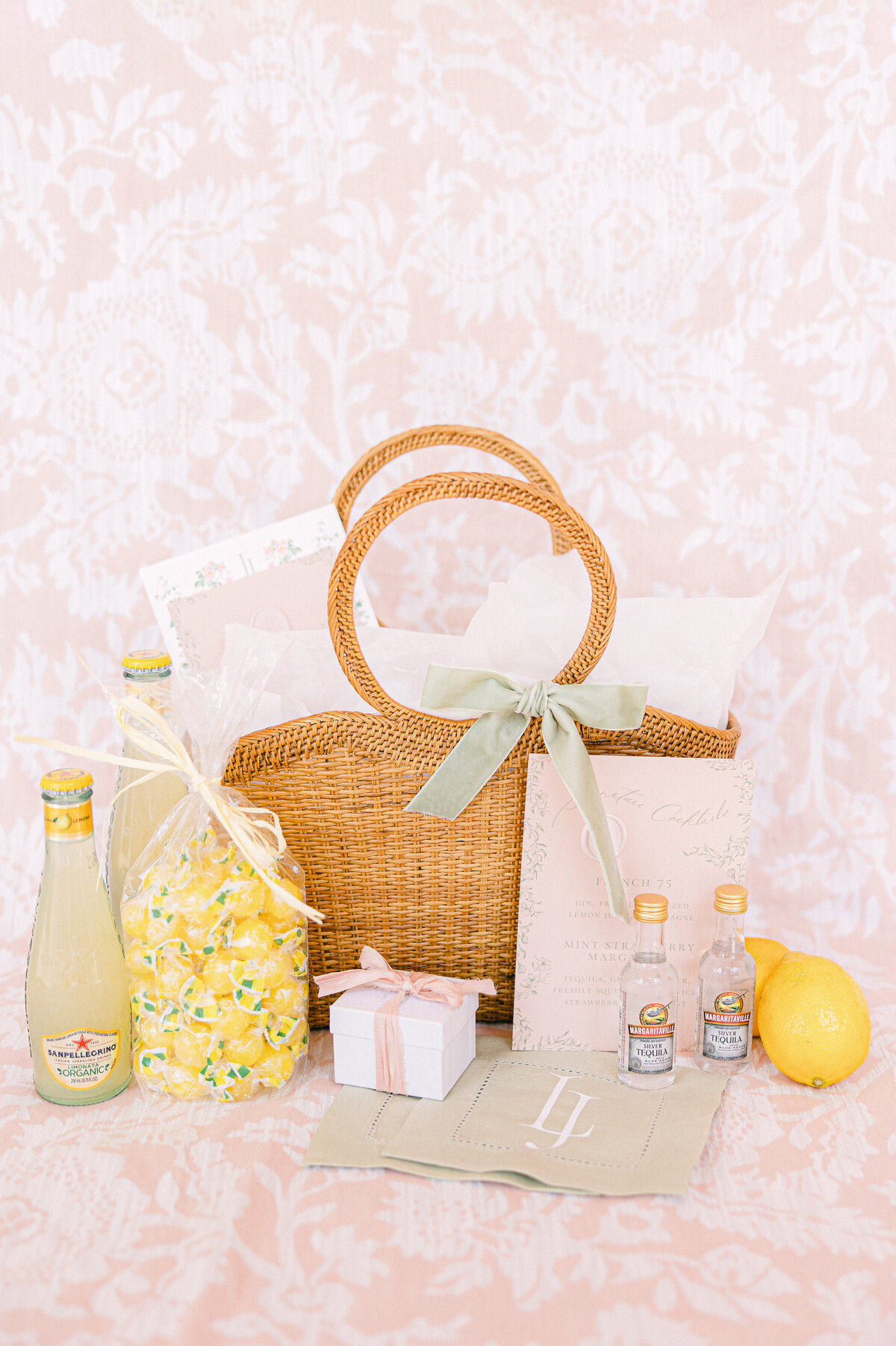 Wicker welcome basket with limoncello bottles, lemon candies, and pastel stationery—detail from a Ringling Museum wedding in Sarasota, captured by luxury wedding photographer Amia Marcell.