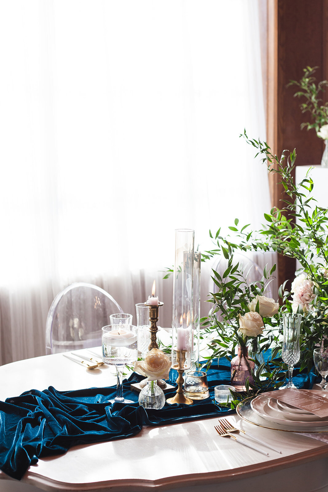 a teal table runner decorated with candles and greenery