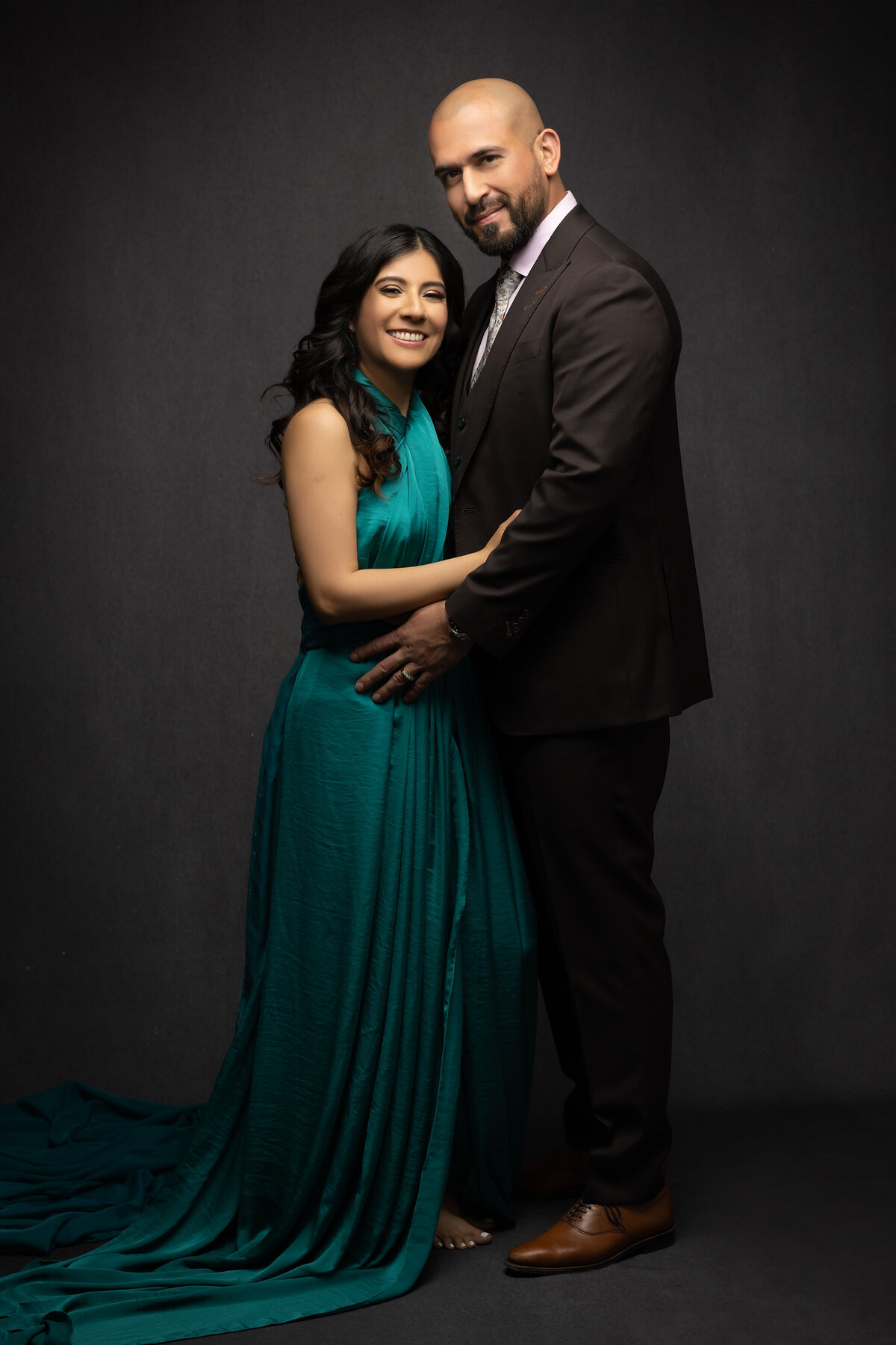 Family photographers in Dallas capture an intimate moment between a couple, with a flowing teal dress and a brown suit.