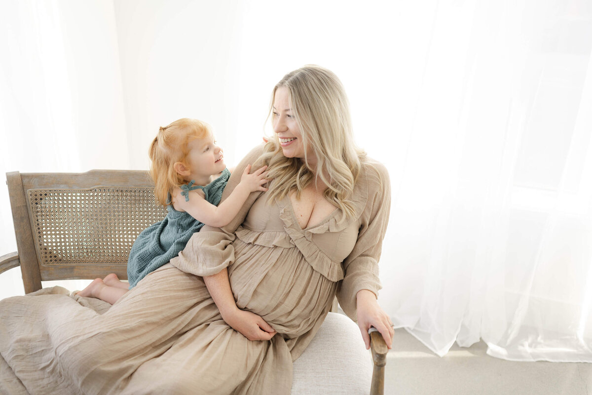 adorable moment between mom and daughter laughing as they prepare to bring another baby into the world near edmond