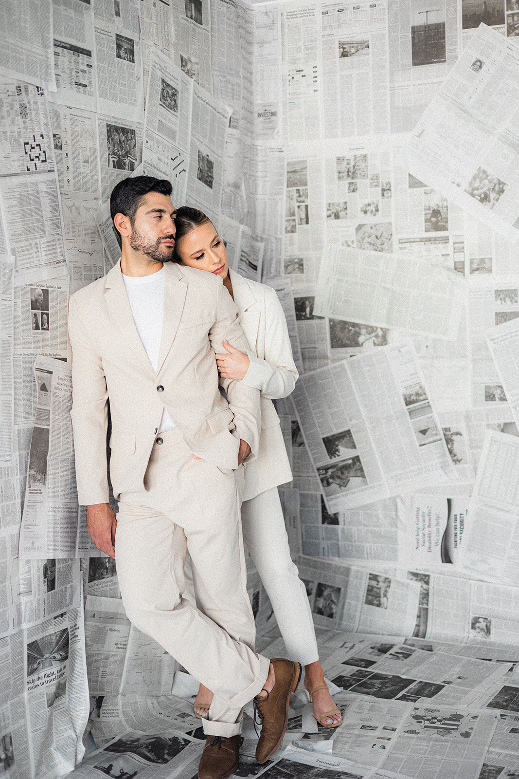 A couple hugs in front of newspapers