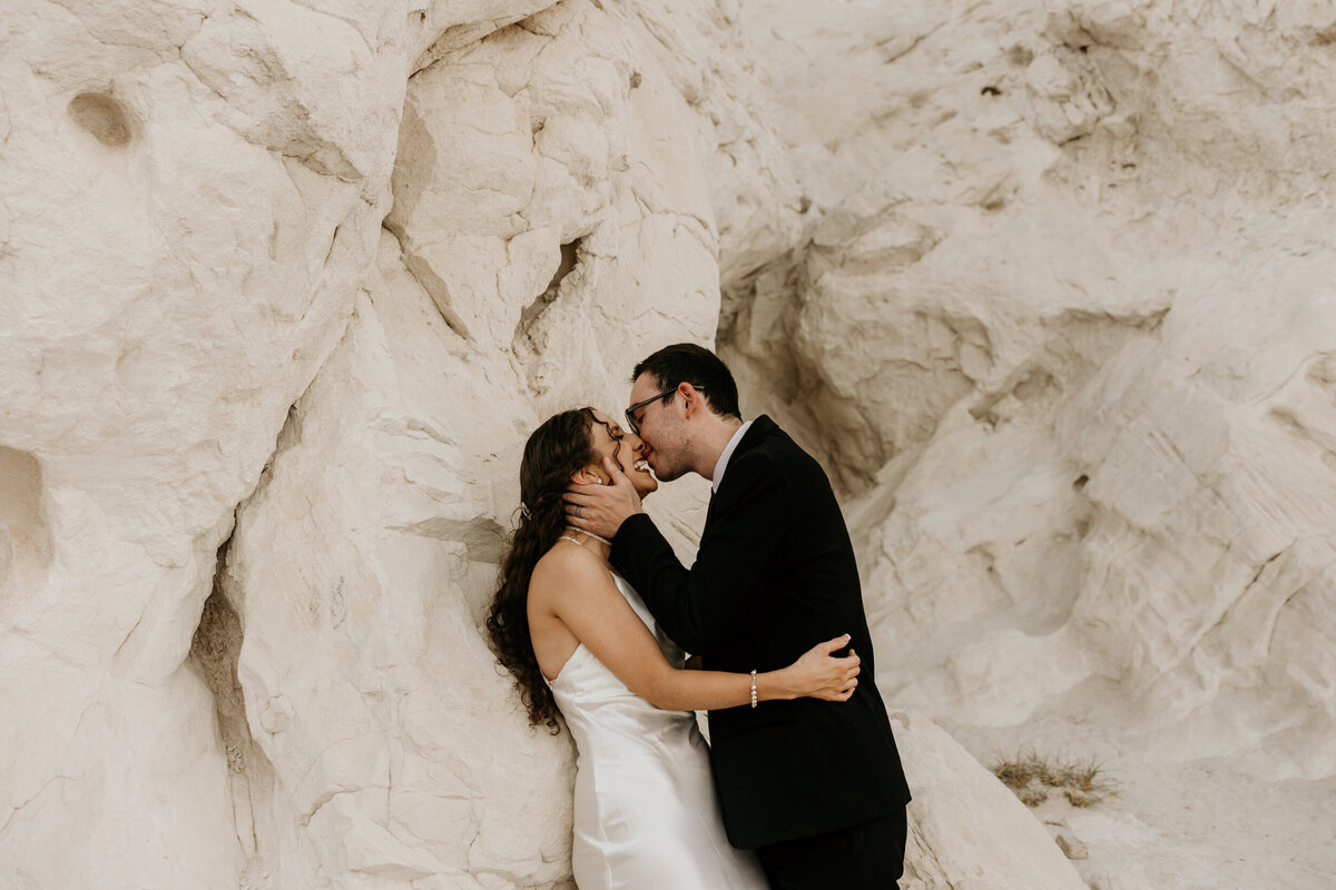 brie and groom kissing against a white rock in New Mexico