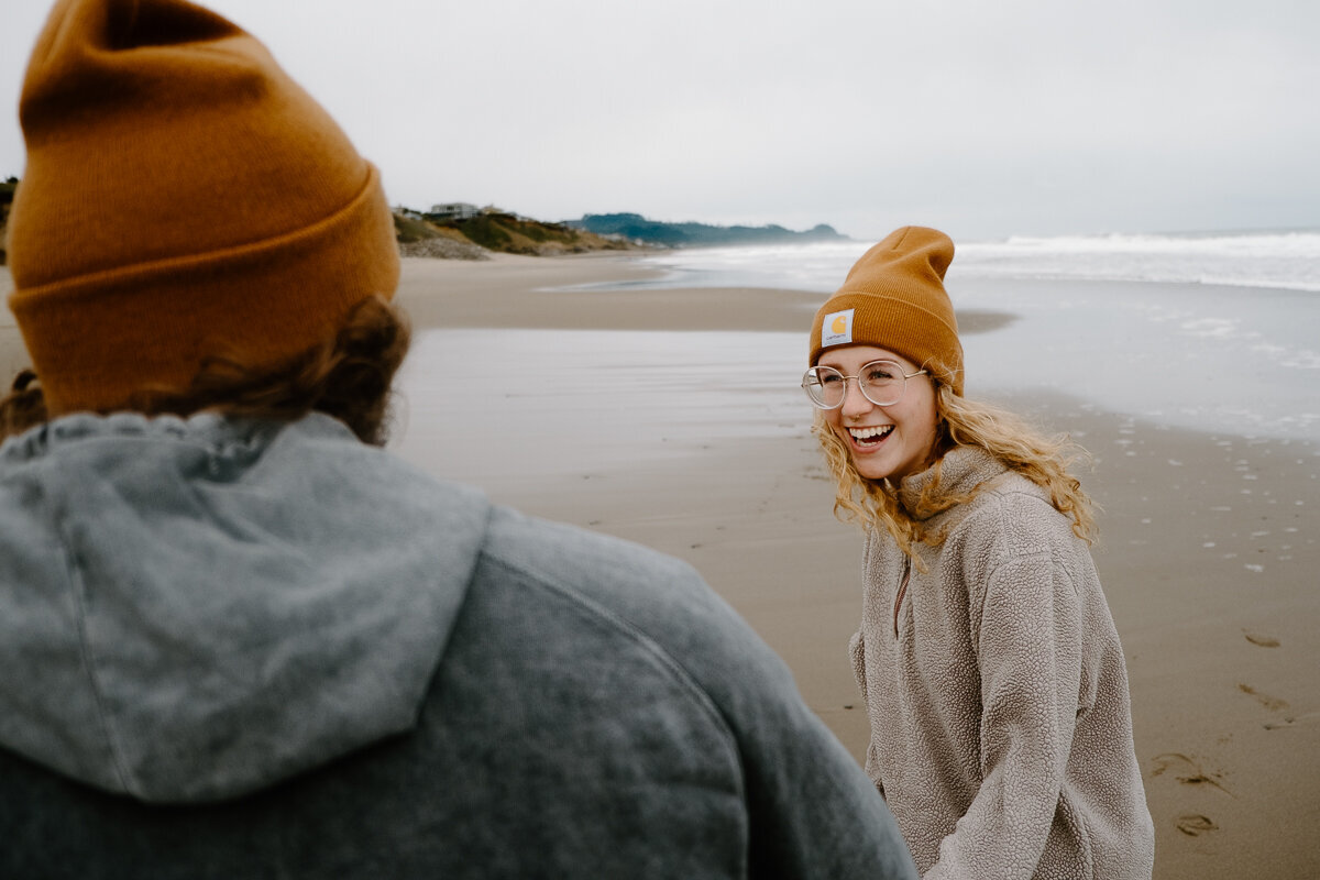 A girl smiles at her boyfriend on the beach in Oregon.
