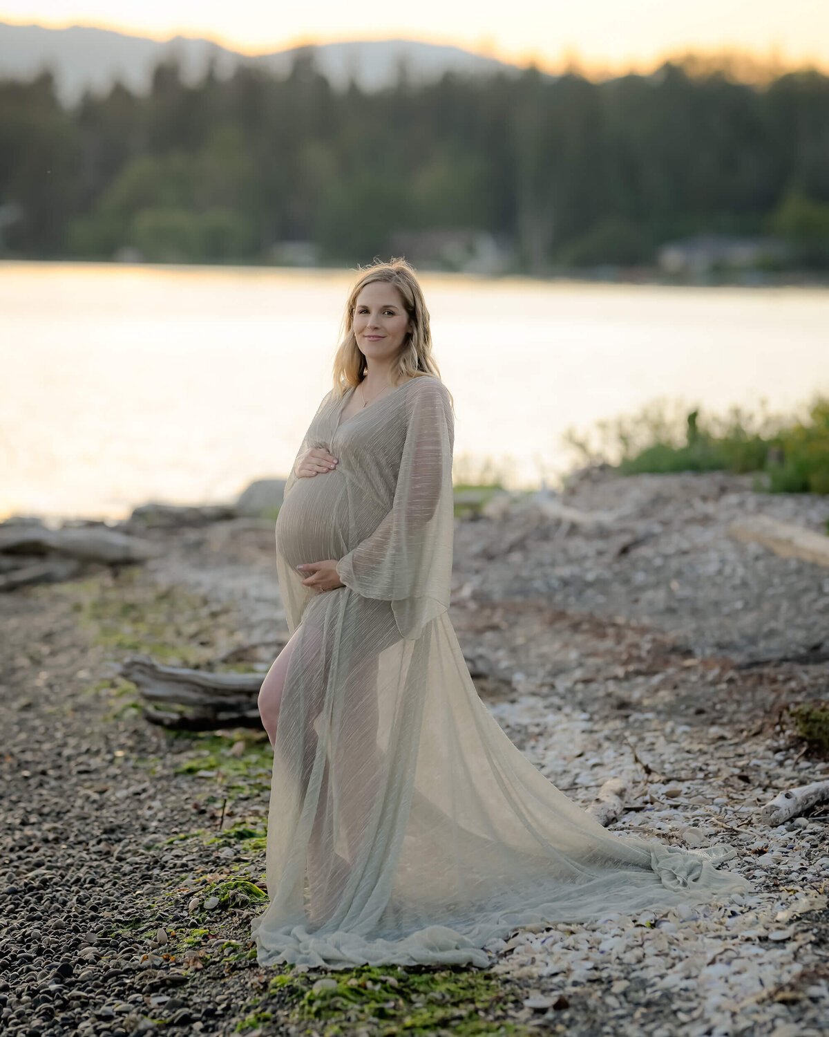 The mom-to-be shines in a sheer golden dress on the PNW beach. Image by E. Benecki photography