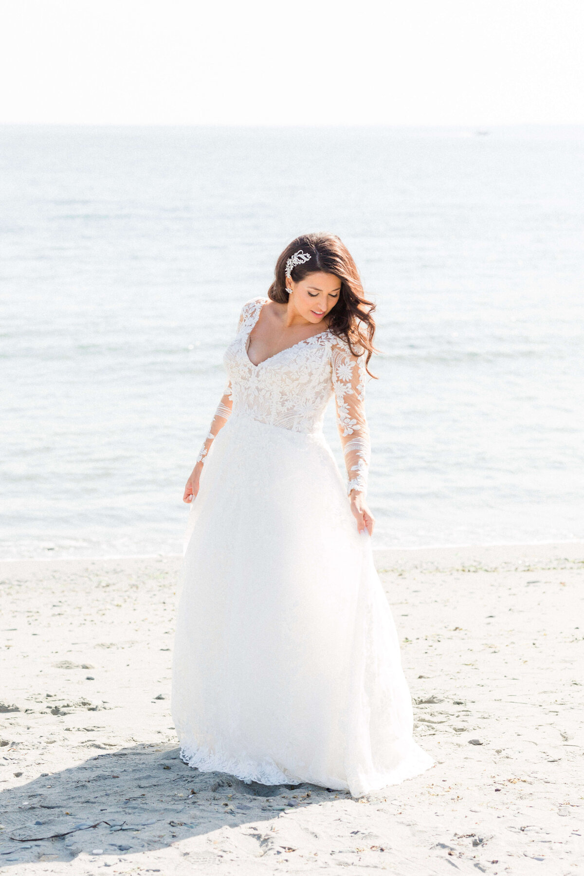 bride holding dress on the beach at castle hill inn newport