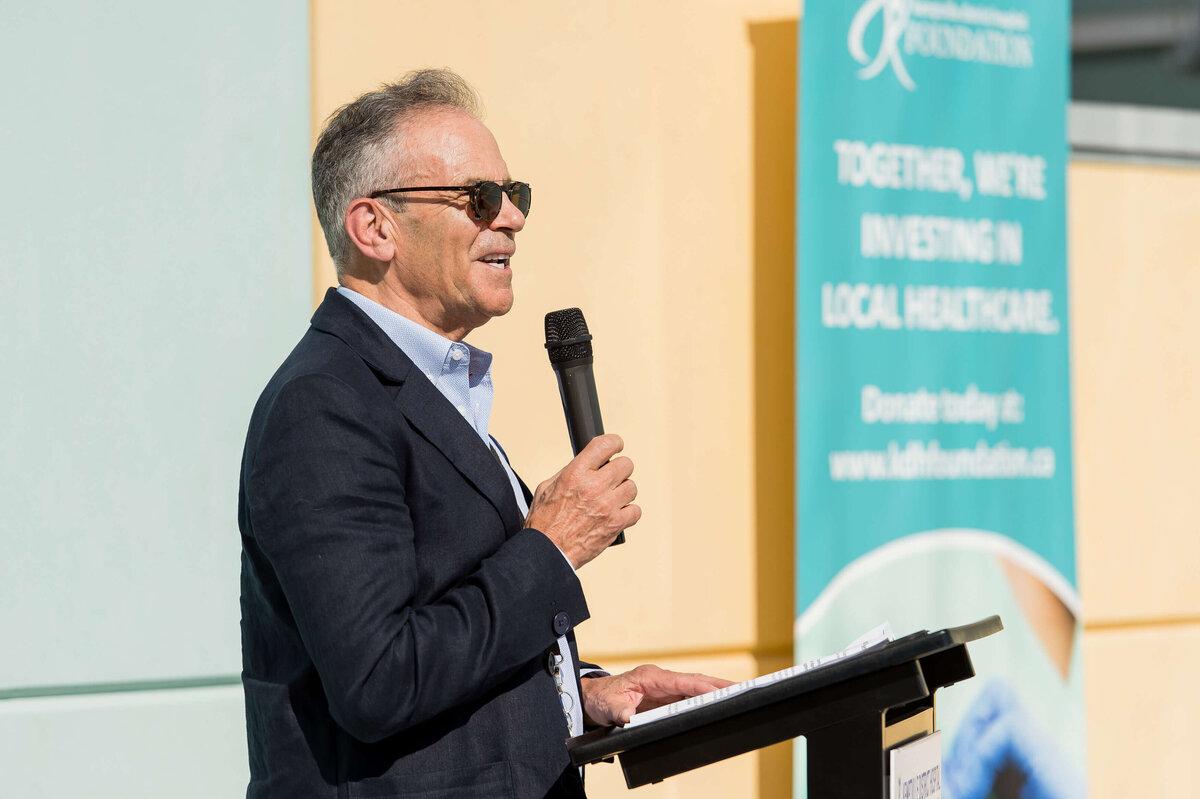 The CEO of KDH speaking into a microphone address attendees of the CT Suite Grand Opening.  Captured by Ottawa Event Photographer JEMMAN Photography COMMERCIAL
