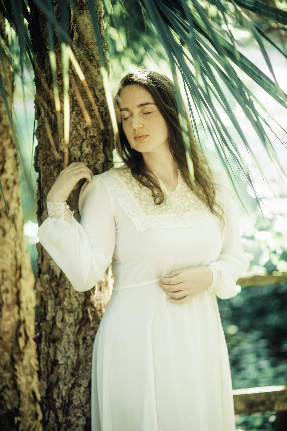 Portrait Photo Of Young Woman In White Dress Leaning At a Tree Los Angeles