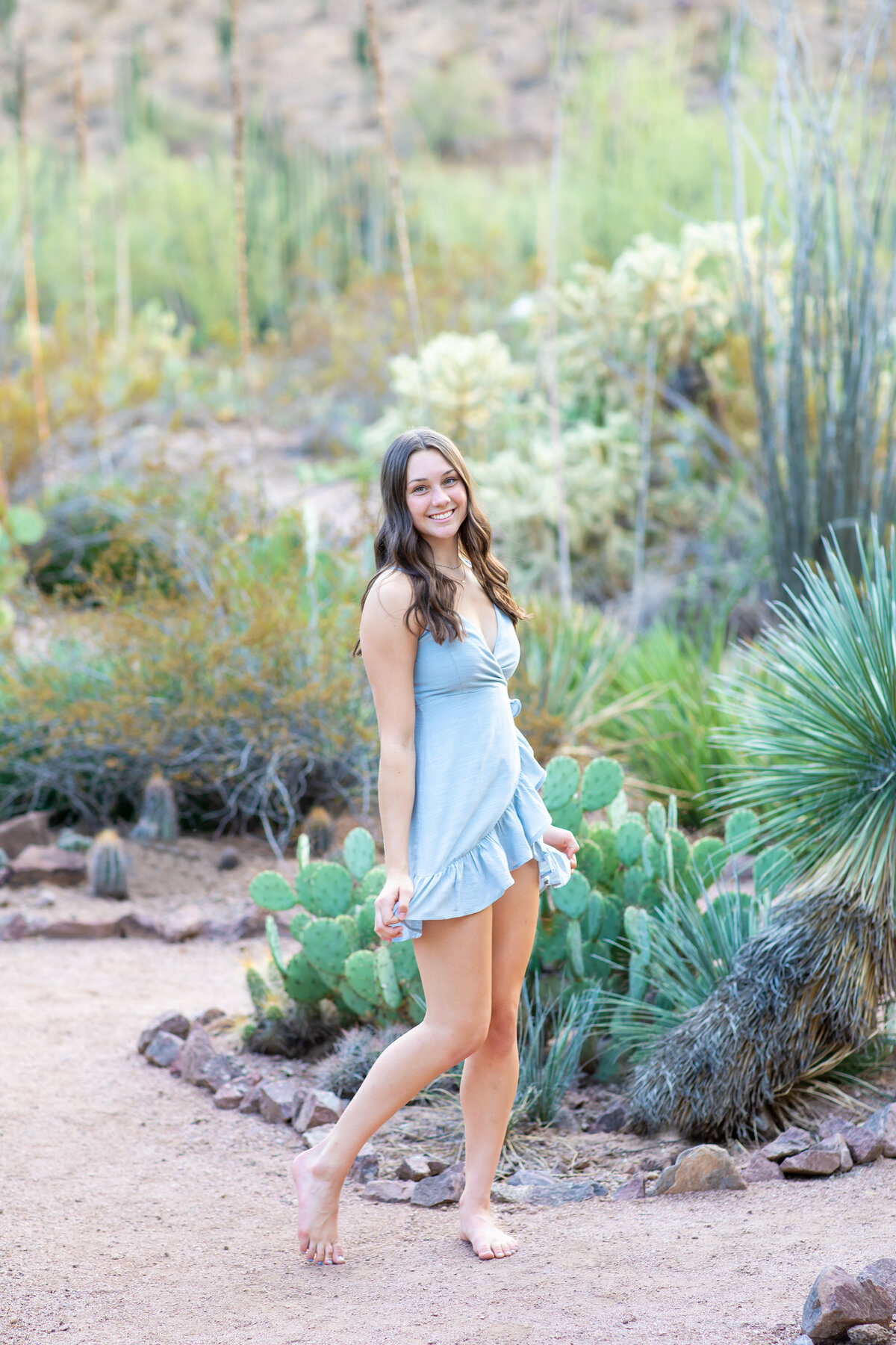 Senior girl twirling in blue dress with cactus Popago Park AZ