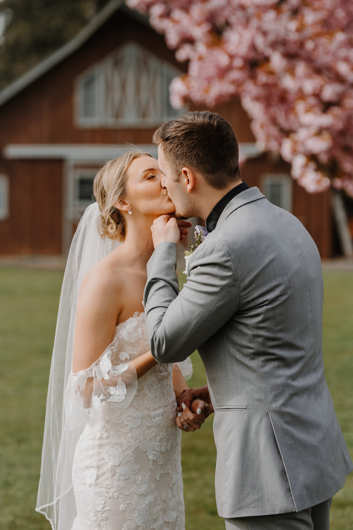 Bride and groom kissing in front of tree with pink flowers