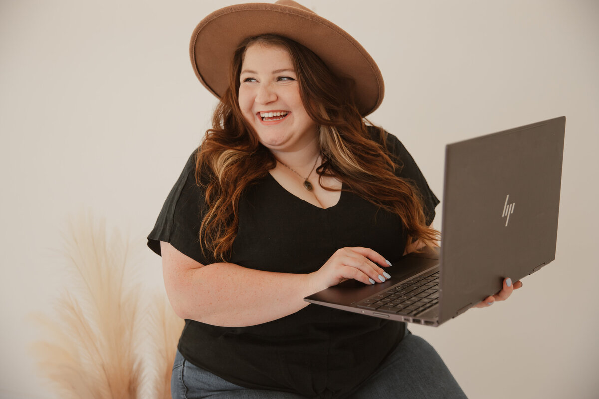 Madeline Murdock, owner of Mad Impact Design, typing on laptop