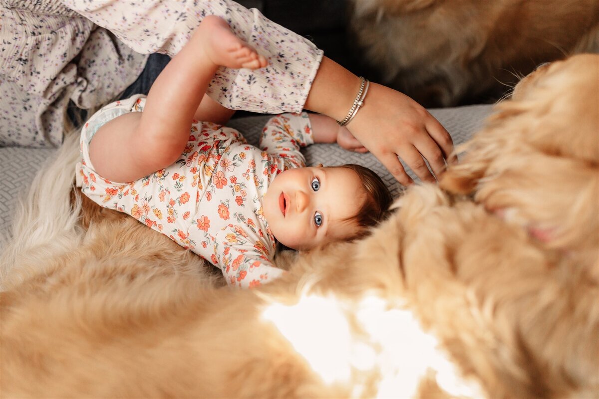 a one year old baby laying with her dog