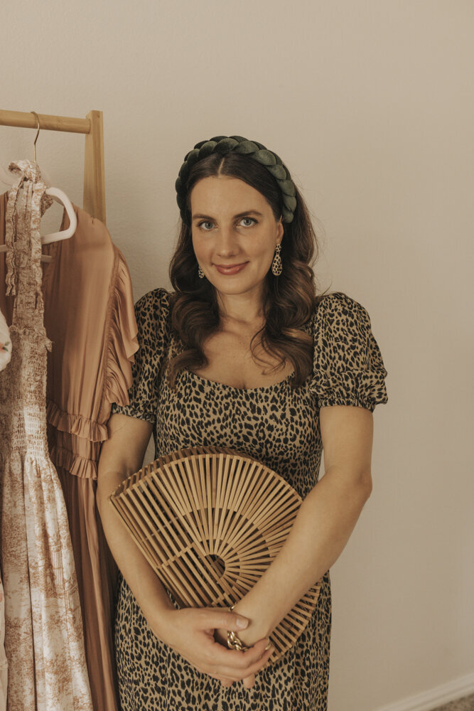 a woman in a patterned dress holding a wooden fan