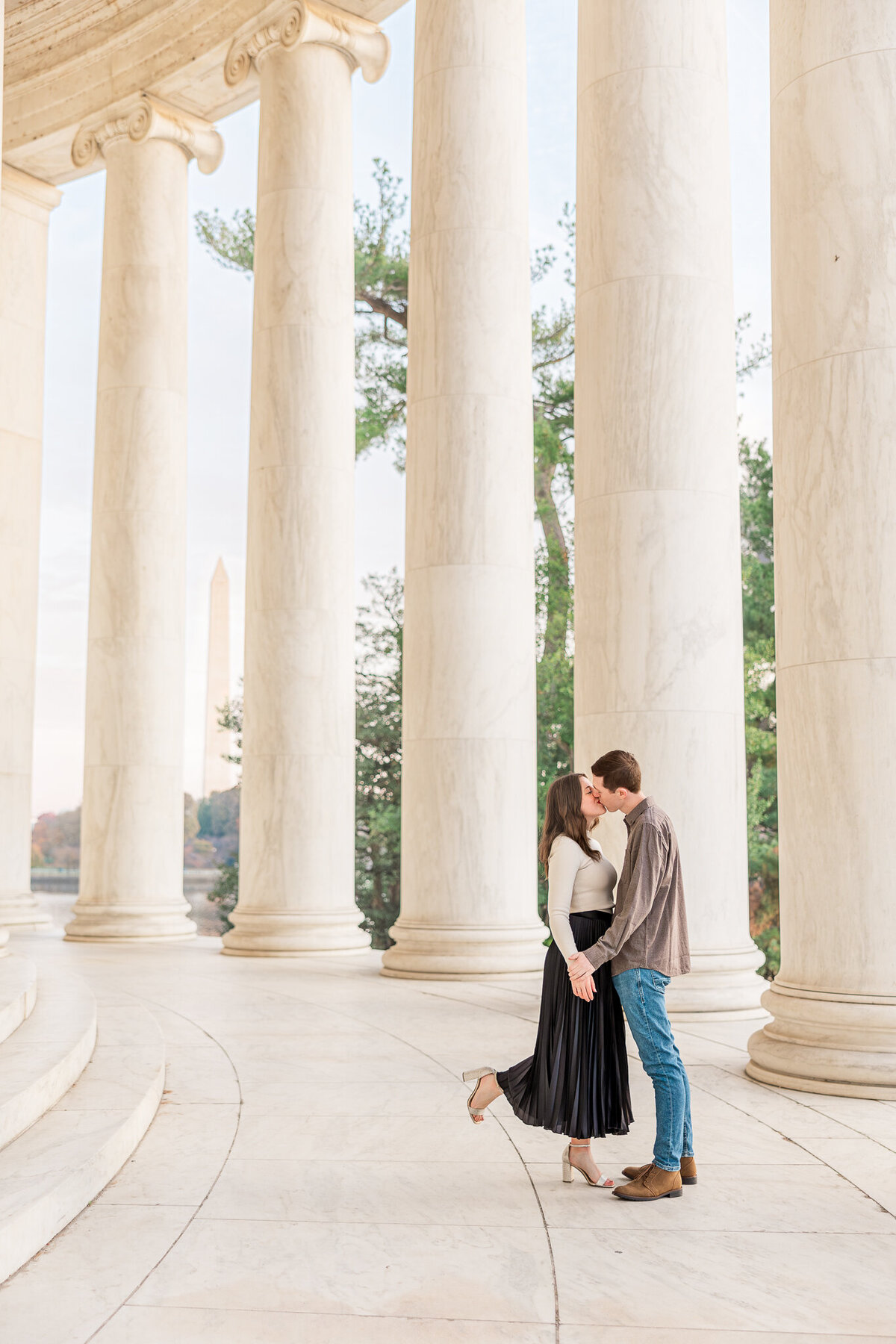 man and woman kissing in the Jefferson Memorial with the Washington Monument in background