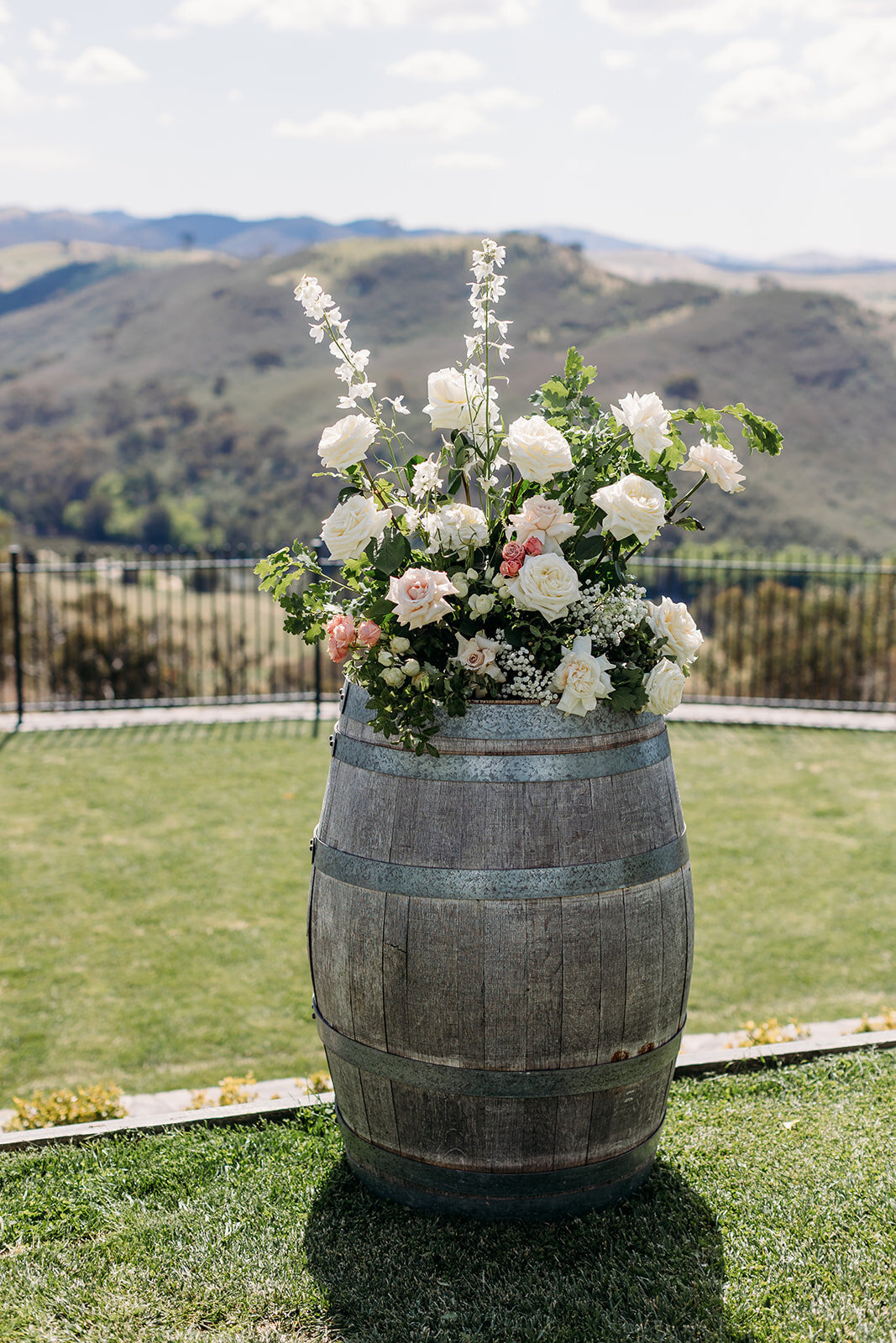 Close up florals on a wine barrel used as arbor decor for a wedding at Brindabella Hills Winery. Floral arrangement by Sunshine Events