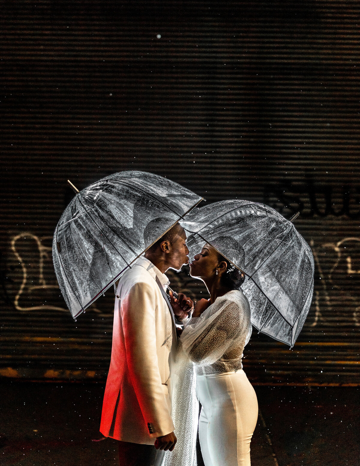 A couple kissing while holding clear umbrellas.
