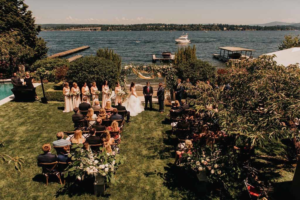 A wedding ceremony in Madison Park private residence at the shores of Lake Washington with large flower arch