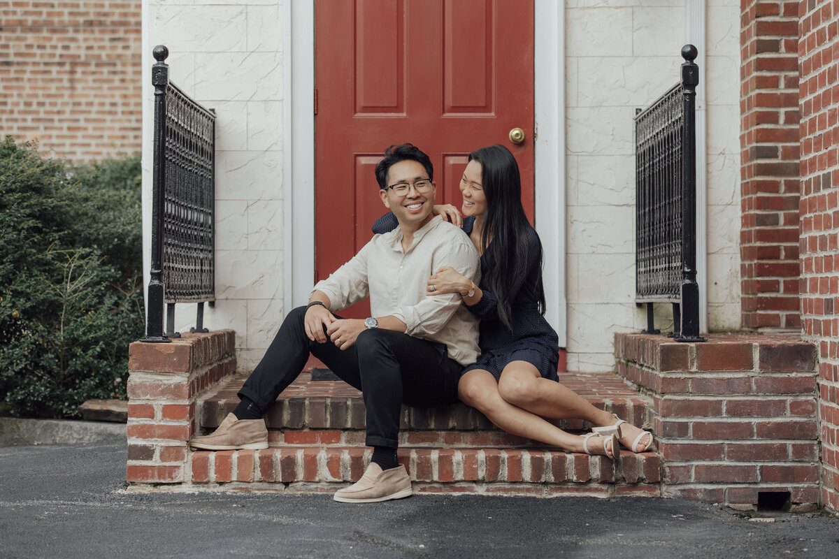 Couple posing by red door during summer engagement photo in Lambertville Hunterdon County New Jersey