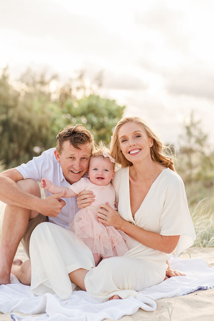 Light and airy family photo on a Brisbane beach: Family of 3 capturing candid moments at sunset.