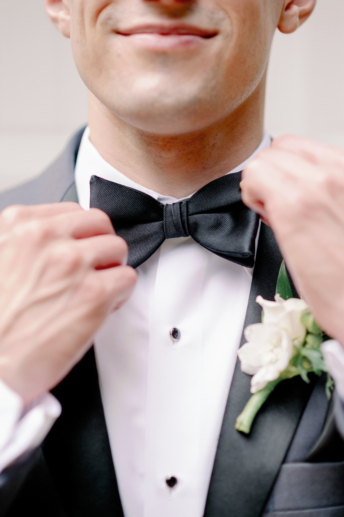 close up of a groom adjusting his bow tie