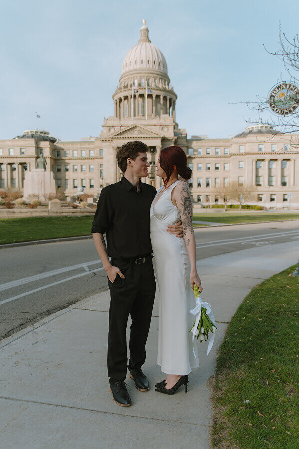 Standing in front of the capitol building in Boise, ID, a couple  stands nose to nose on their elopement day.
