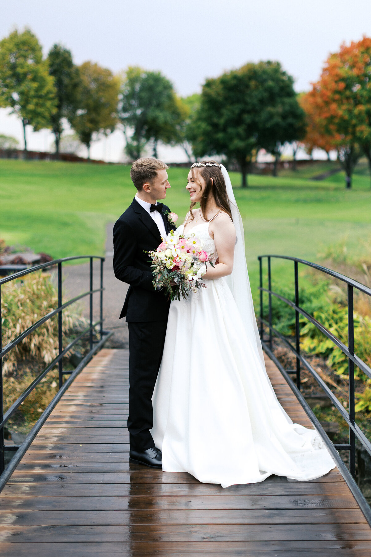 Bride and groom standing closely together on the bridge at Minneapolis Golf Club, gazing into each other's eyes in an intimate moment — captured by Minnesota wedding photographer.
