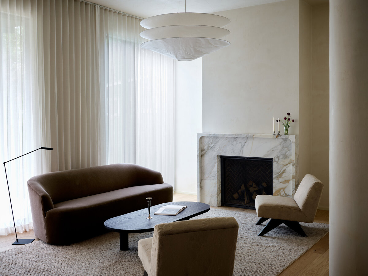 marble-fireplace-plaster-living-room-natural-light-austin-home-belgian-modern-jeanneret-chair-house-franc