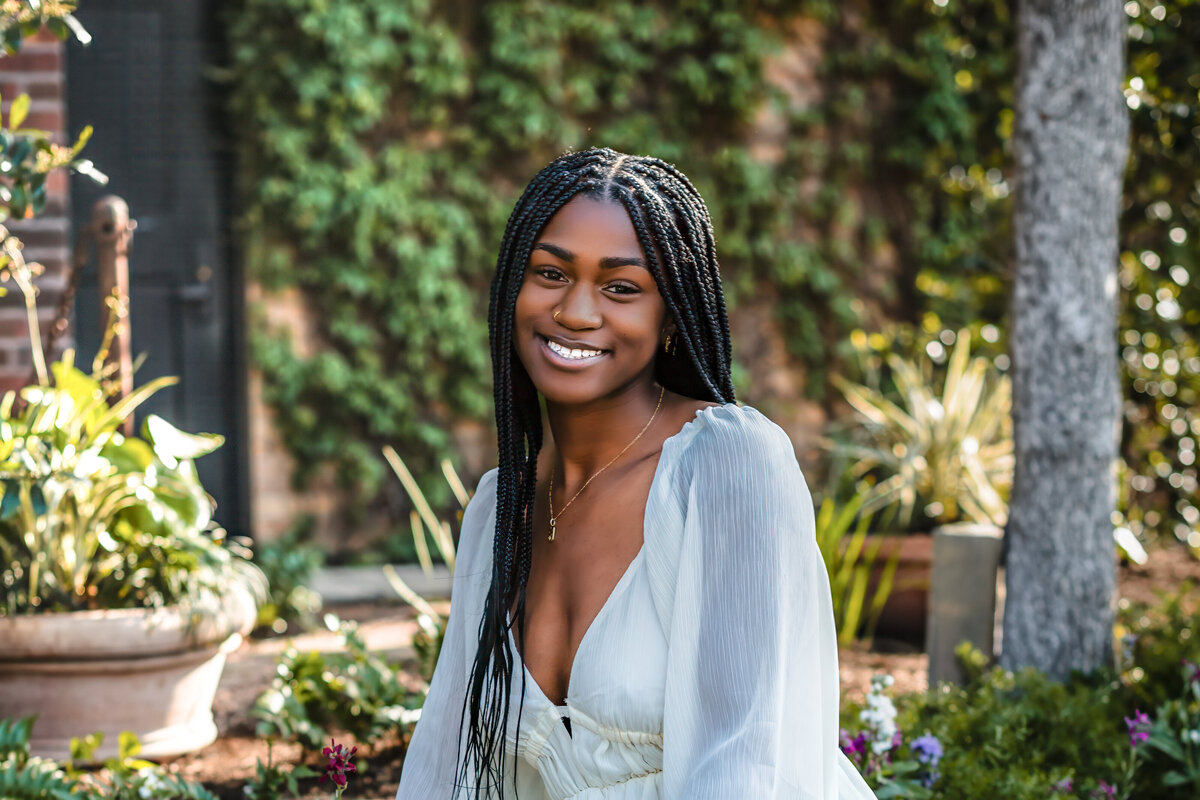 High school senior sitting on steps in white dress at The Pearl, joyful and natural.