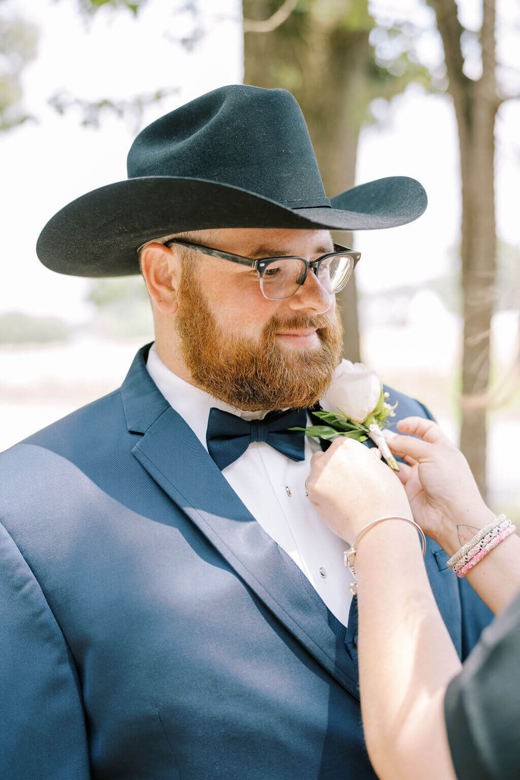 groom's mother putting boutonniere on groom