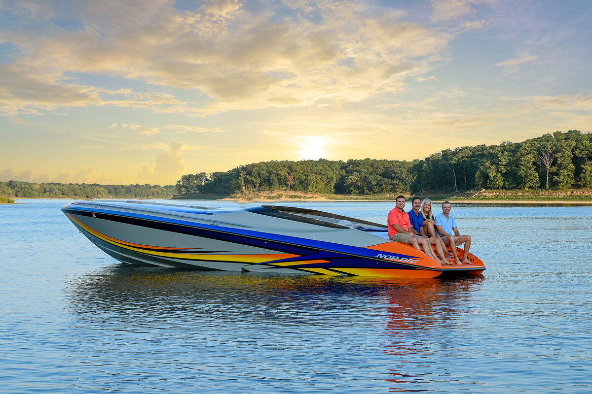 A small family sits on the back of their speed boat in a lake for their Iowa Family Photographer