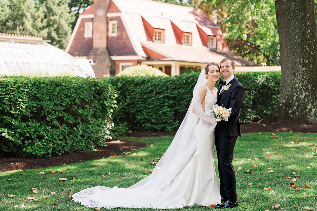 bride and groom posing for wedding photo on the lawn of the frick museum
