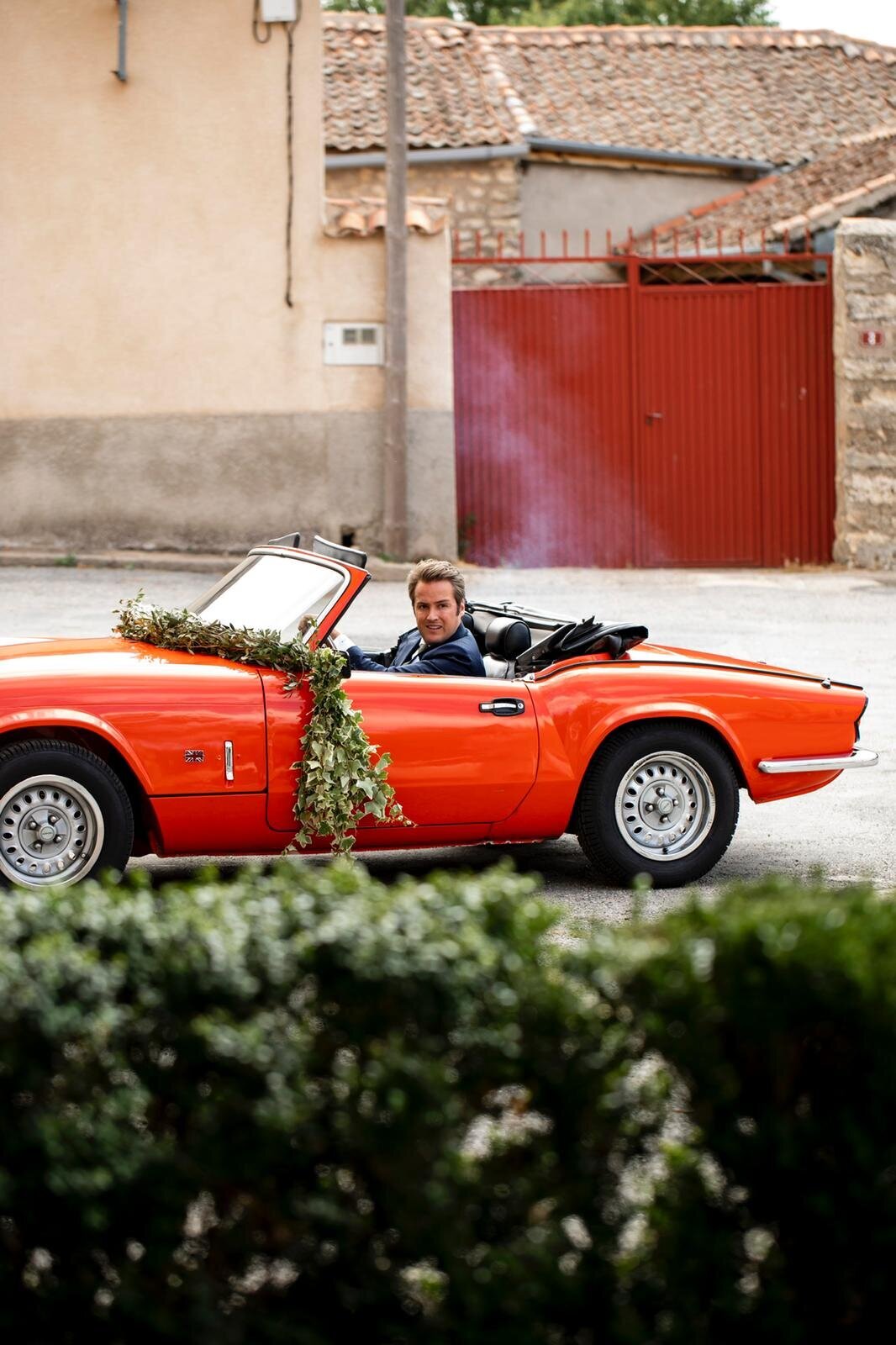 The groom coming to the church with a red classic car