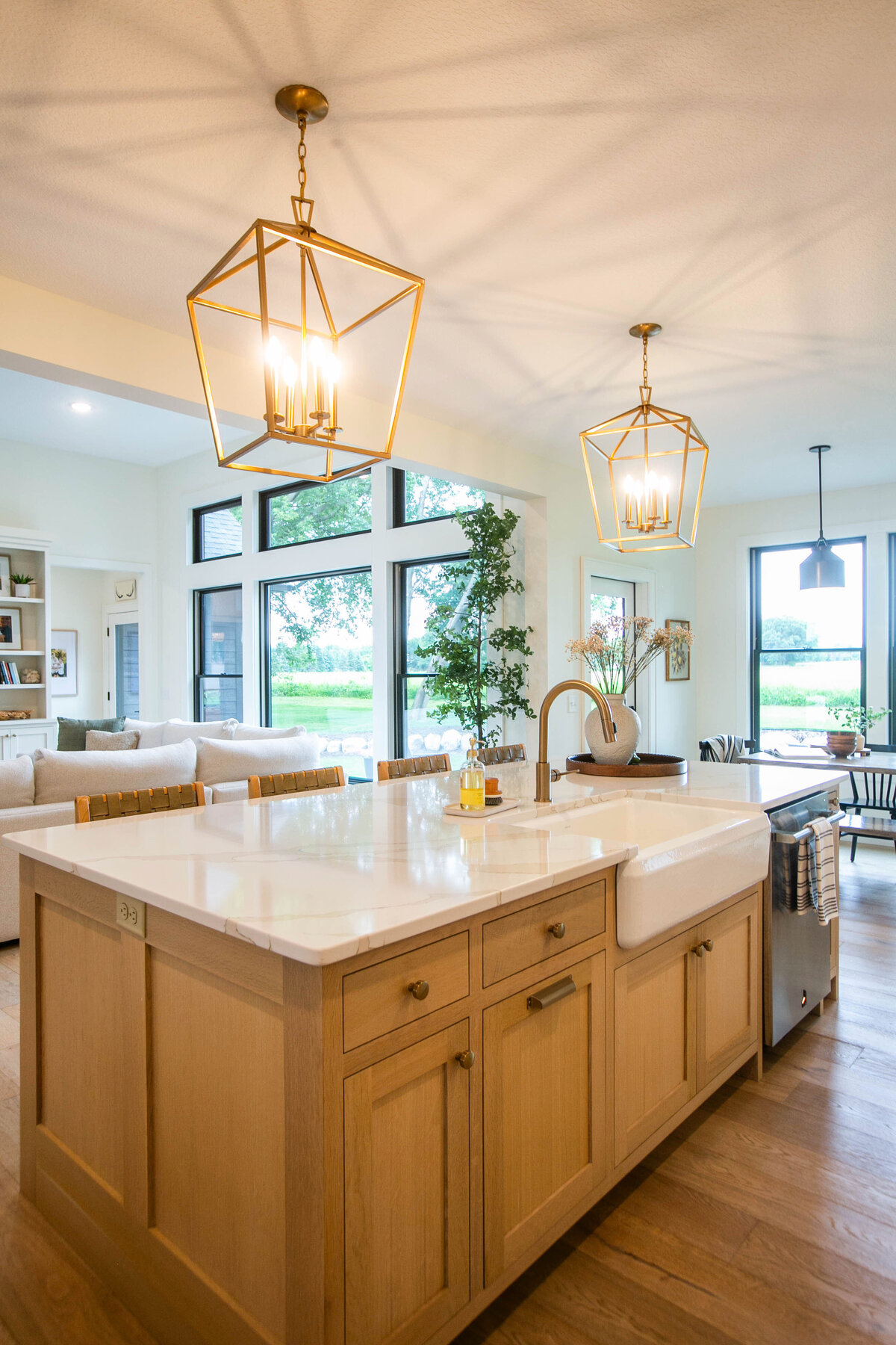 Open kitchen with white cabinets, large island, and quartz countertops in an Otsego custom home