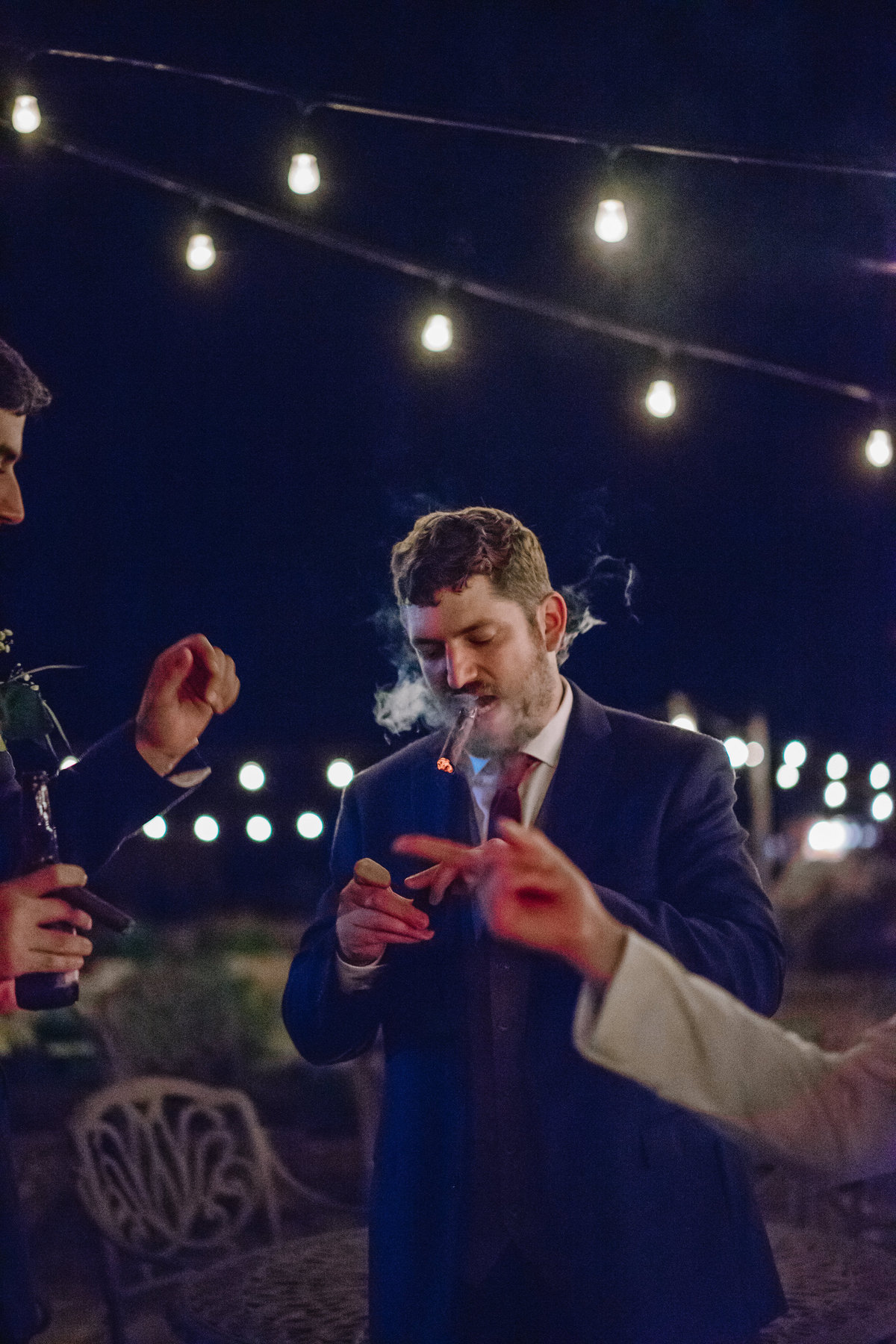 groom smoking a cigar during reception at Welfare Cafe wedding venue in the Texas Hill Country