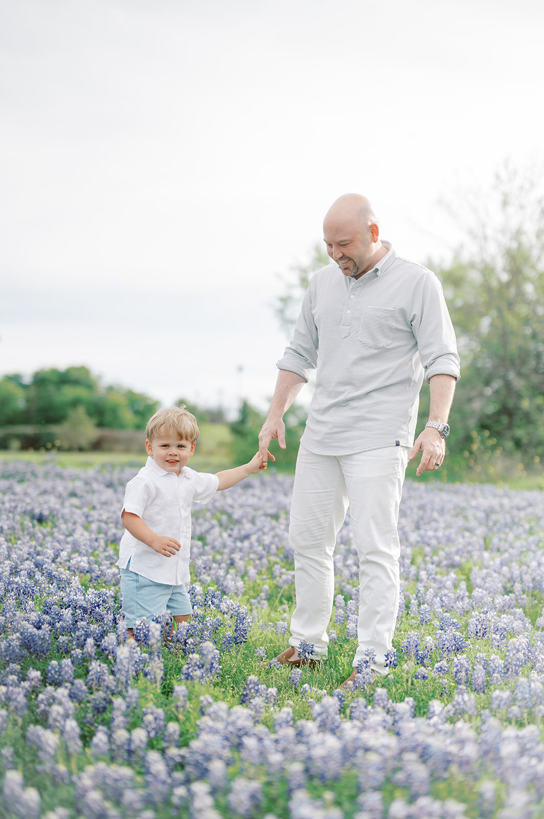 A sweet father-son moment captured in a scenic Dallas bluebonnet field, perfect for spring family portraits.
