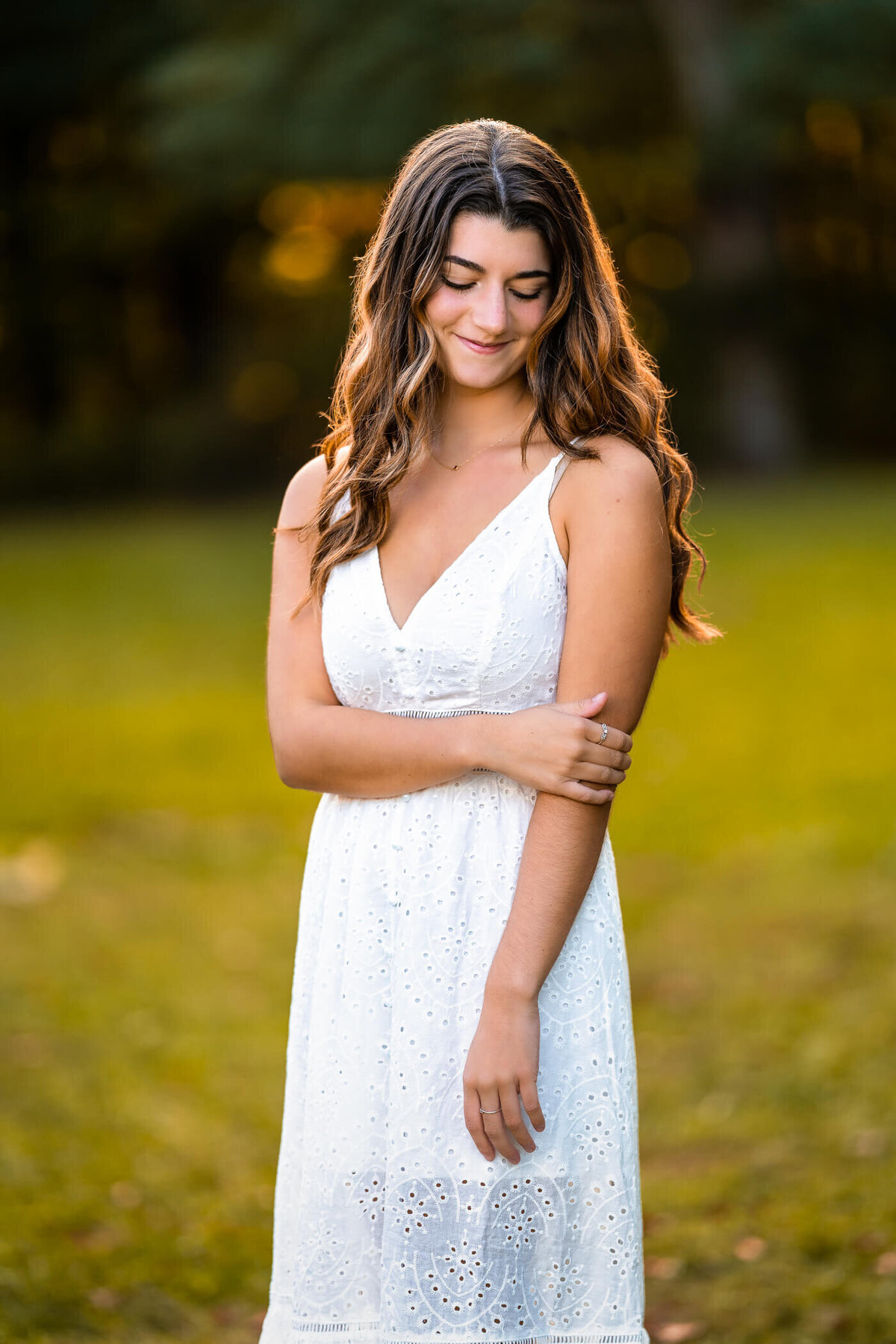 Pittsburgh high school graduation photography of a senior smiling while holding her arm in the field of a local Pittsburgh park