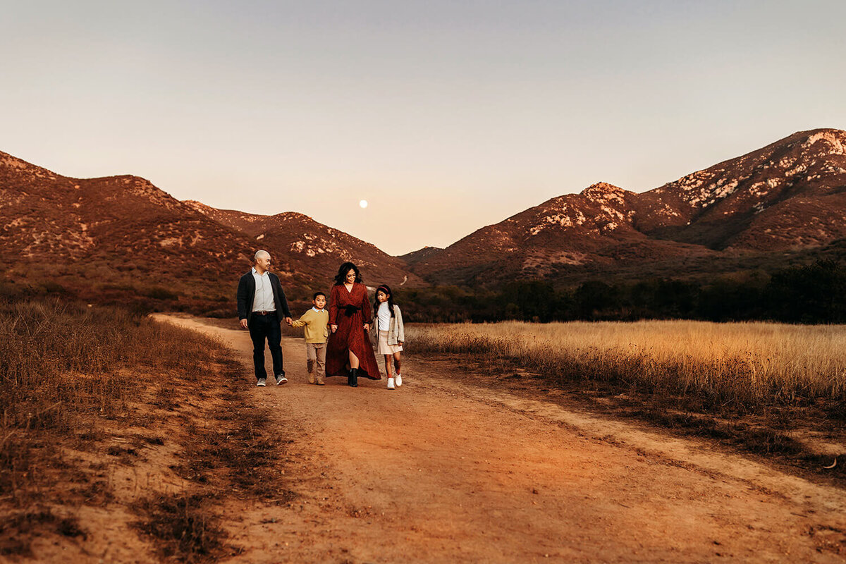 Mom, dad, school aged son and daughter walking through the Estes Park mountains at sunset.