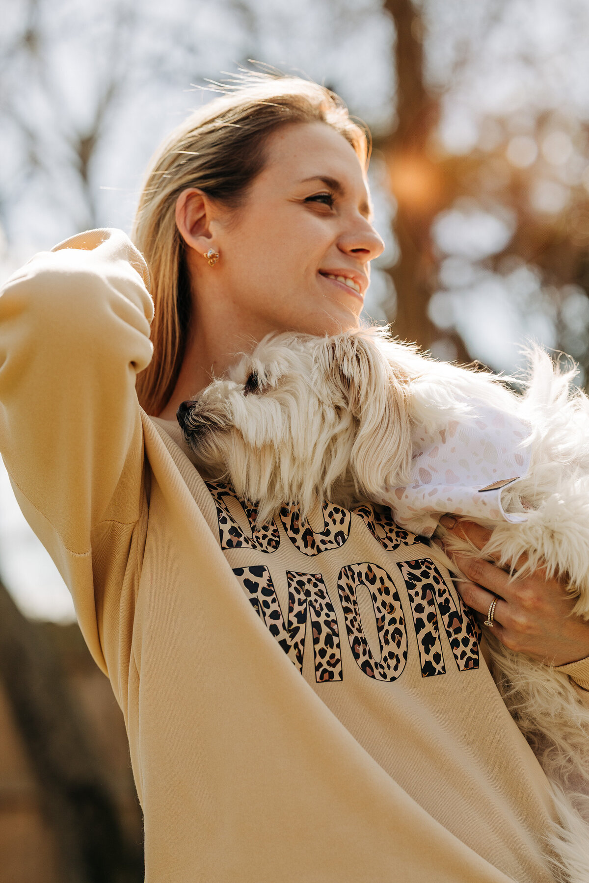 Beautiful portrait, of a young woman during the sunset, holding her dog, golden hour. Posed