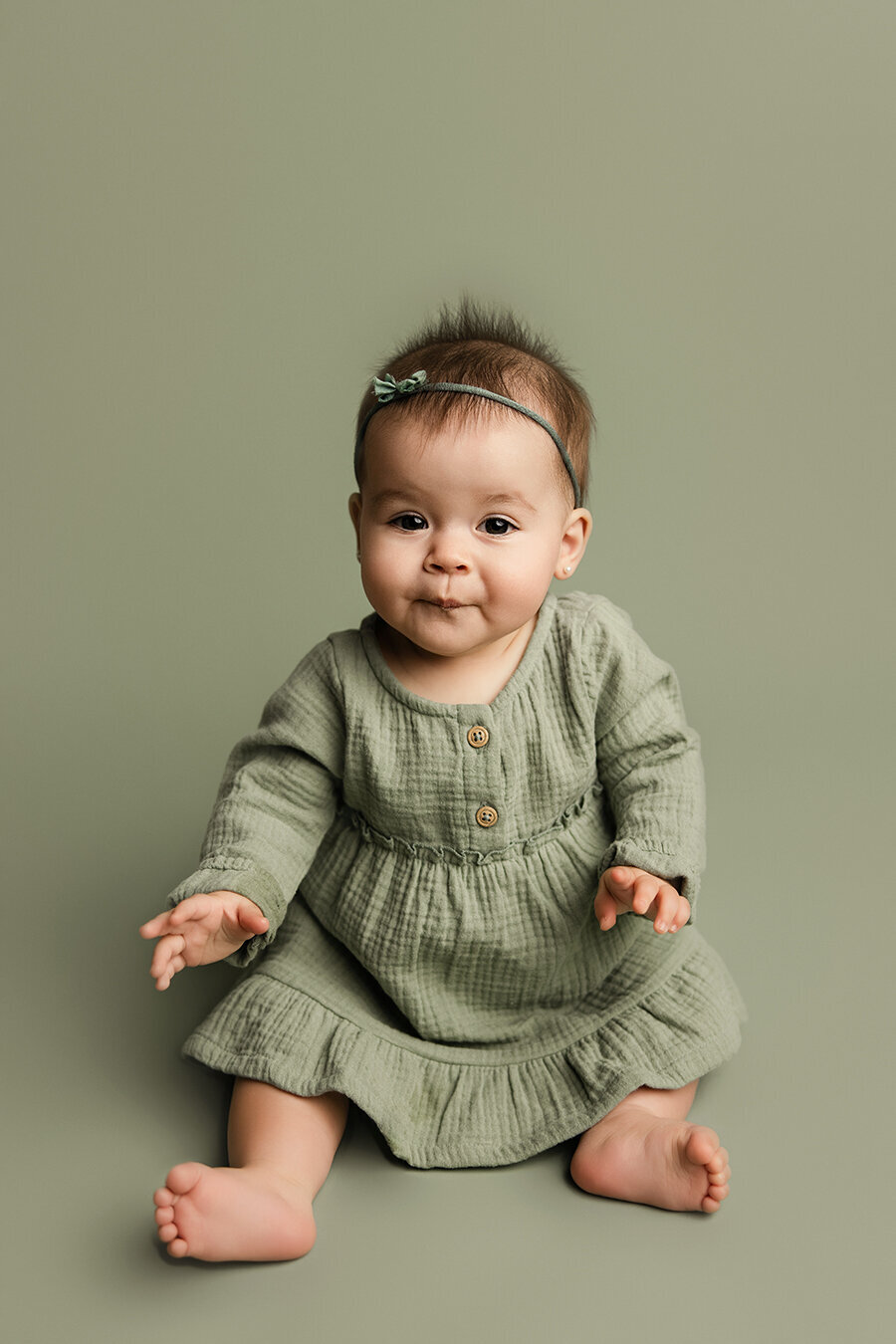 Baby girl sitting in a green dress at her milestone session in Colorado