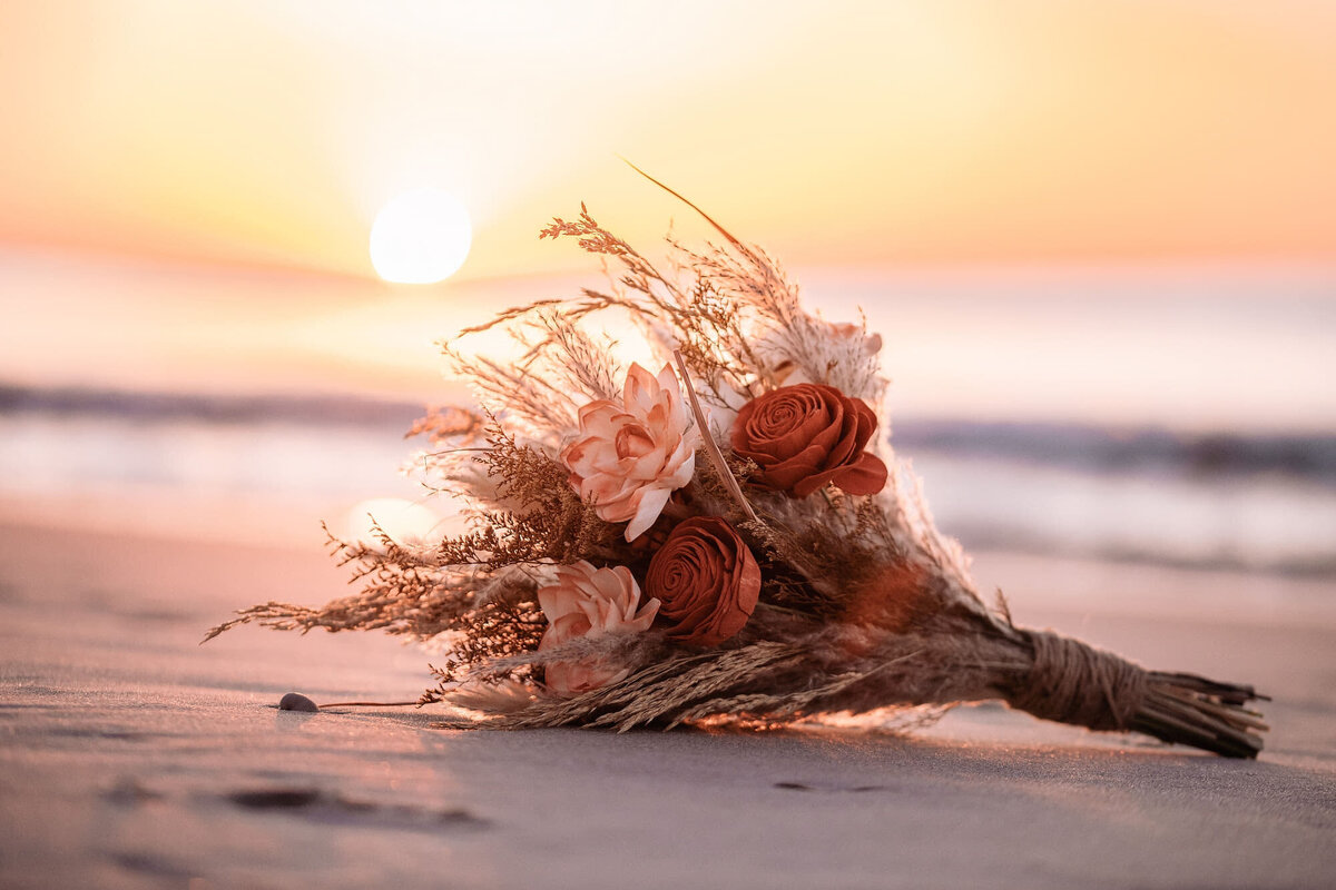 bouquet on a beach with the sunset in the background
