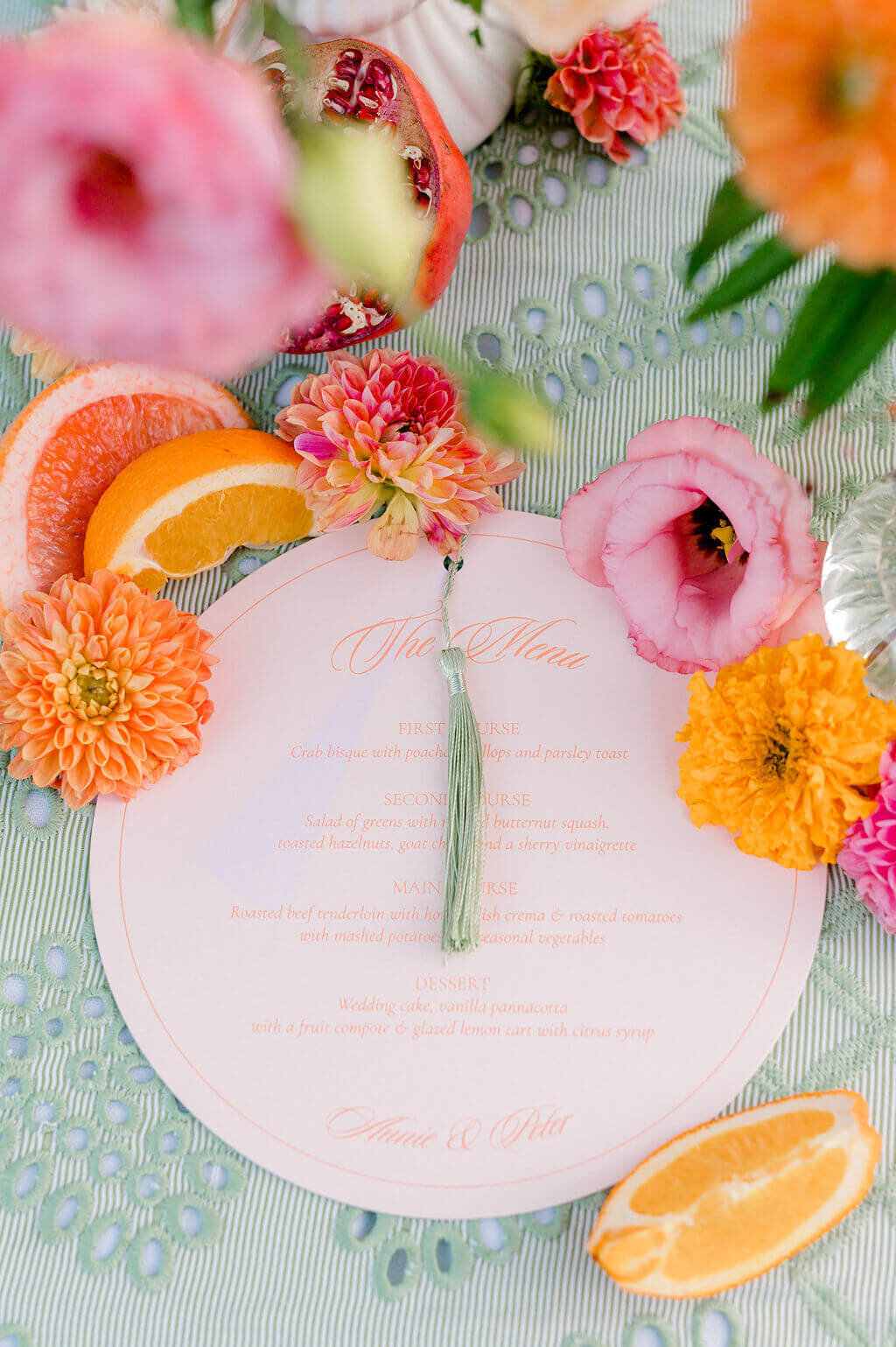 Round blush wedding menu with tassel, styled with citrus slices and florals. Keywords: wedding day stationery, wedding stationery, luxury wedding invitations, wedding invitation designer.