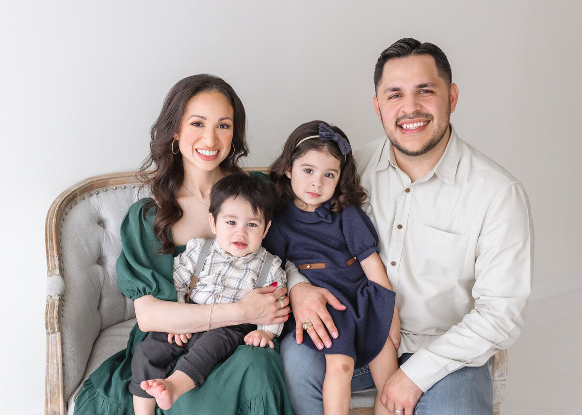 family of 4 smiling and sitting