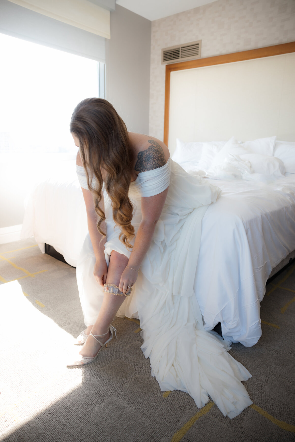 Bride preparing for her wedding day, gently adjusting her veil and dress in a peaceful, light-filled room.