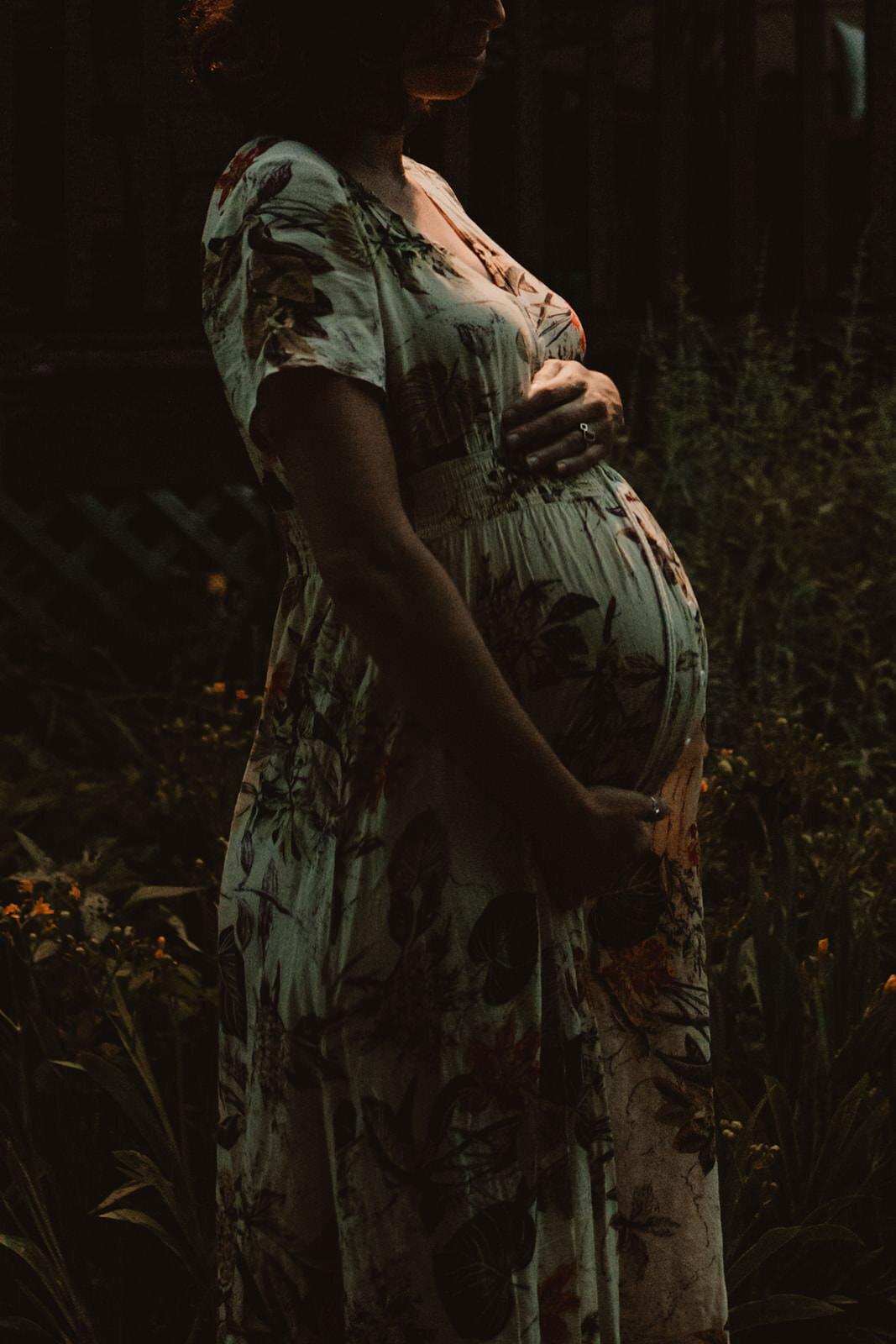 A person in a long dress holding their pregnant stomach 