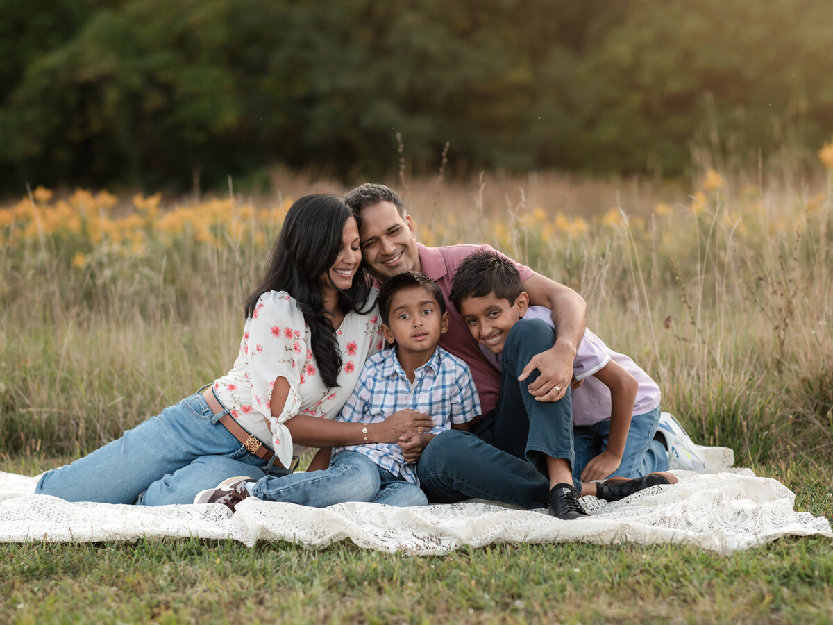 mom dad and two sons posing in field for family photos