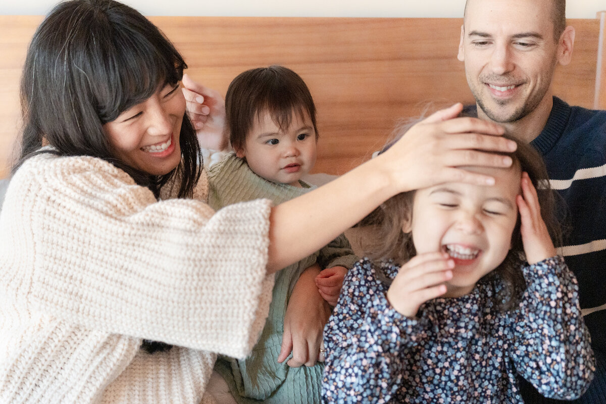family of four on bed smiling